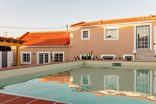 Vista da piscina do apartamento da FC Housing Company em Abrantes, com cobertura em barro e janelas com molduras brancas