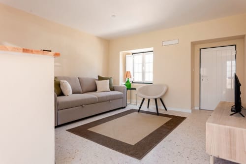 Sala de estar moderna em apartamento da FC Housing Company em Abrantes com sofá cinzento, poltrona e tapete com borda
