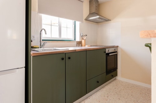 Cozinha moderna no apartamento da FC Housing Company em Abrantes com armários verde oliva, bancada de madeira e aço inoxidável