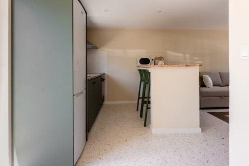 Cozinha e sala integradas modernas no apartamento FC Housing Company em Abrantes com balcão ilha branco e verde