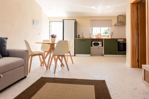 Cozinha e sala de estar modernas de T1 na FC Housing em Abrantes com mesa de refeições, móveis verdes e luz natural