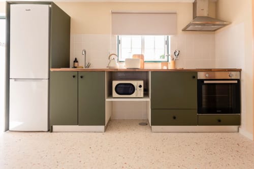 Cozinha moderna no apartamento da FC Housing Company, Abrantes PT, com armários em tom azeite, bancada de madeira e aço inoxidável