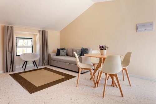 Apartamento T1 luminoso na FC Housing Company, Abrantes: sala moderna com sofá, mesa de refeições, cadeiras e grandes janelas