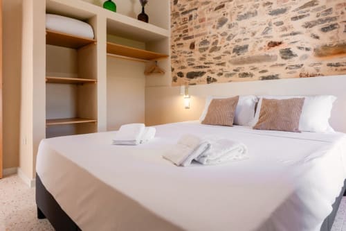 Quarto moderno no apartamento da FC Housing Company em Abrantes com cama queen, parede de pedra, guarda-roupa embutido e detalhes listrados
