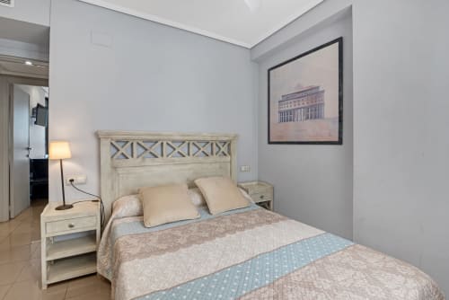 Bright bedroom with cream wooden bed, beige pillows, and architectural print at Pataconablue sea-view apartment in Valencia