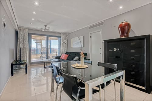 Modern sea-view apartment in Valencia with dining area, black furniture, balcony overlooking the coast, and contemporary