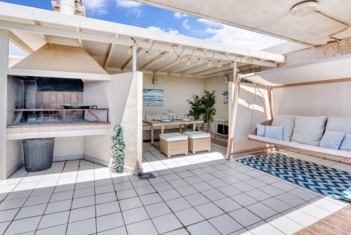Spacious beachfront penthouse terrace in Valencia with BBQ, lounge seating, dining area, and sea views