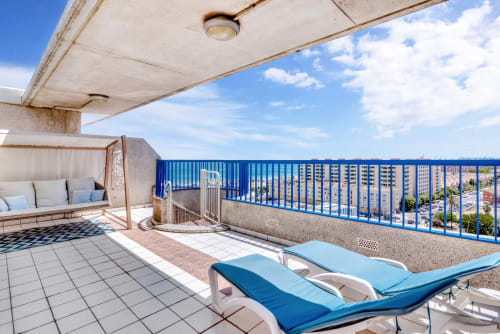 Oceanfront terrace at Pataconablue Rentals in Valencia with loungers, sea views, and blue railings overlooking the beach and