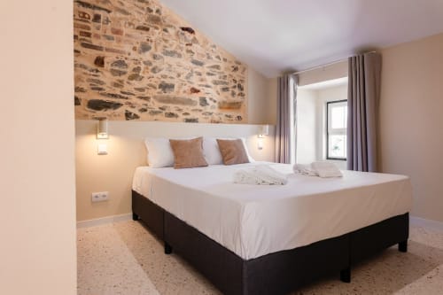 Quarto moderno da FC Housing Company em Abrantes com cama de casal, parede de pedra e vista para a piscina