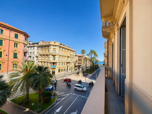 Vista della strada di Sanremo dal balcone della Suite Ingrid con edifici colorati, palme e architettura mediterranea
