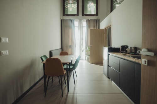 Elegante zona pranzo in moderno appartamento a Palermo con tavolo, sedie, angolo cottura e vista sulla città.