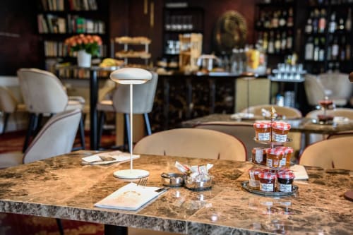 Élégant espace de restauration de l'Hôtel Splendid Cannes avec table en granit, sièges modernes et présentation de conserves gastronomiques