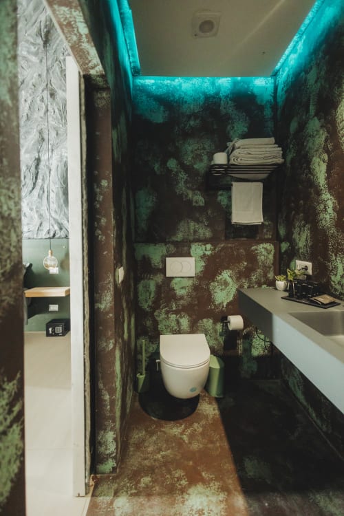 Bagno con pareti turchesi coperte di muschio, toilette bianca, lavabo, portasciugamani e portarotolo presso Oltre Exclusive