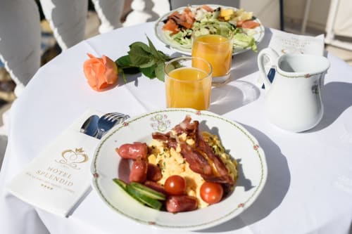 Petit-déjeuner élégant à l'Hôtel Splendid Cannes avec œufs, bacon, légumes frais, jus et centre de table en rose corail