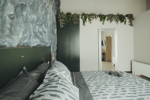 Camera da letto moderna presso Oltre Exclusive a Palermo con biancheria a righe, testata verde, piante sospese e vista sulla città