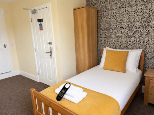 Single room at The Cornerhouse hotel in Somerset with wooden bed, damask wallpaper, and modern amenities including TV and