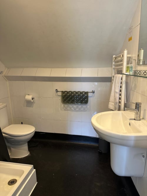 Clean modern bathroom at The Cornerhouse hotel in Somerset with toilet, pedestal sink, and black floor