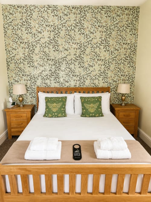 Superior Double Room at The Cornerhouse Somerset with wooden bed, green patterned wallpaper, white linens, and welcome