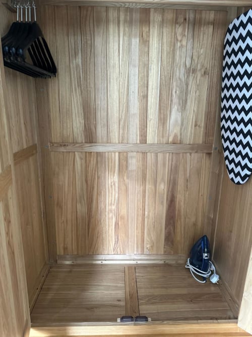 Empty wooden wardrobe closet with shelf, hangers, and ironing board in Superior Double Room at The Cornerhouse, Somerset