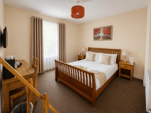 Superior Double Room at The Cornerhouse hotel in Somerset, featuring wooden bed, desk, TV, and warm beige décor