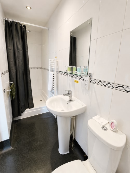 Modern bathroom in Superior Double Room at The Cornerhouse, Somerset, featuring white tiles, pedestal sink, toilet, shower