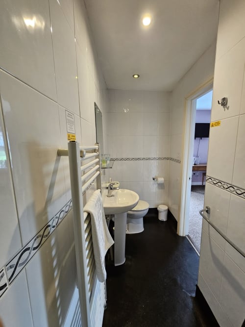 Modern bathroom in Superior Double Room at The Cornerhouse Somerset with white tiles, pedestal sink, heated towel rail, and