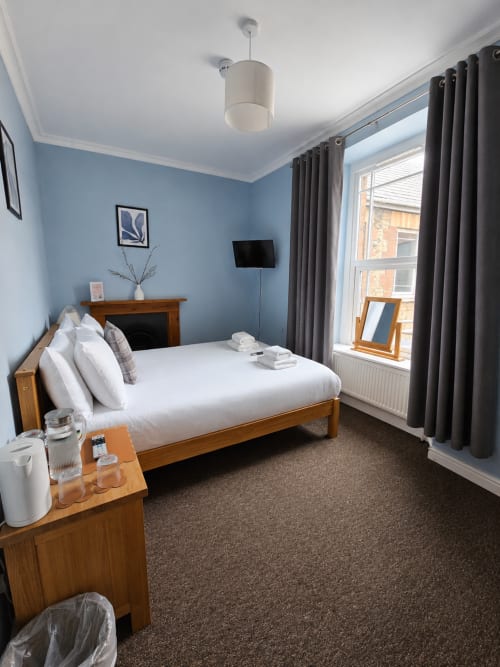Cornerhouse hotel double room in Somerset with blue walls, wooden bed, flat-screen TV, and large windows with dark curtains