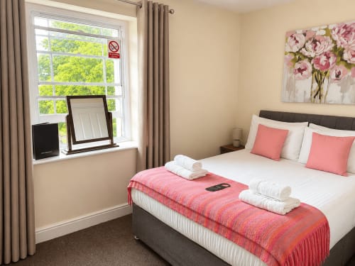 Cozy double bedroom at The Cornerhouse hotel in Somerset with white bedding, pink accents, and bright window view