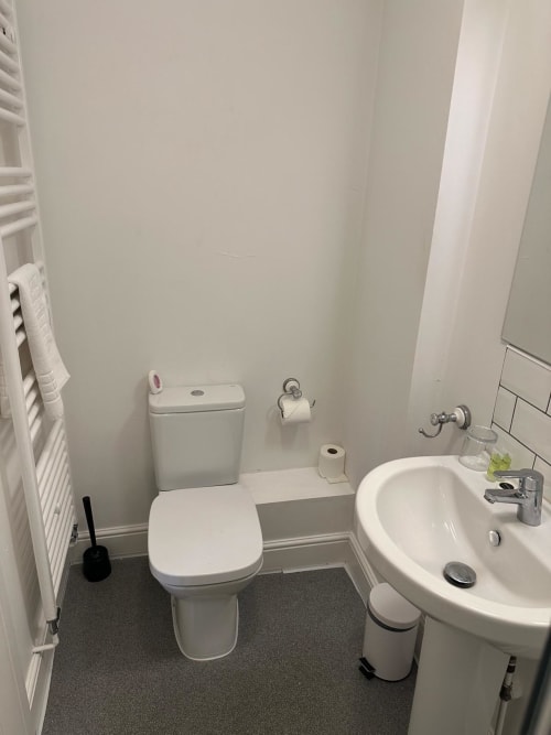 Clean modern bathroom at The Cornerhouse hotel in Somerset with white toilet, circular sink, and heated towel rail