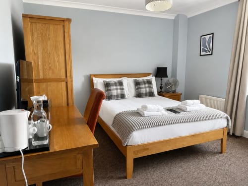 Cornerhouse double room in Somerset with wooden bed, desk, and modern amenities including TV and fan