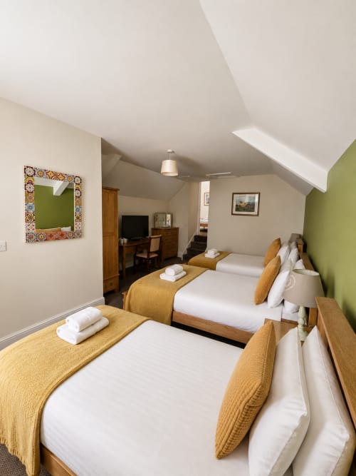 Family Suite at The Cornerhouse Somerset with three beds, wooden furniture, green accents, and modern amenities