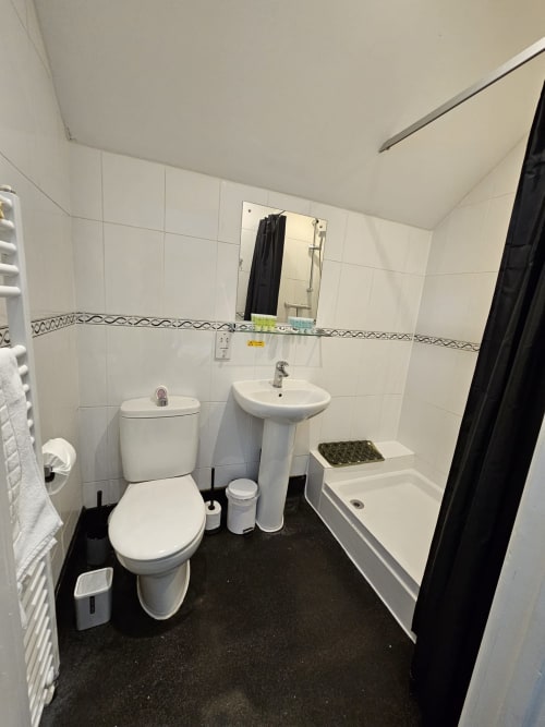 Modern bathroom in The Cornerhouse Family Suite, Somerset, with toilet, pedestal sink, bathtub and black floor