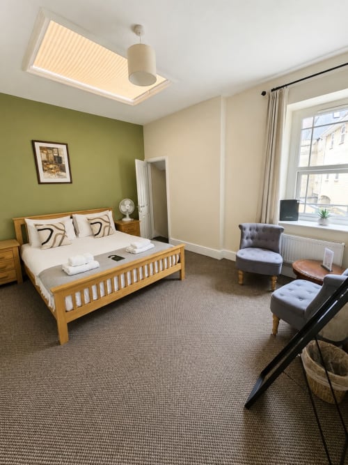 Family Suite at The Cornerhouse hotel in Somerset featuring wooden bed, green accent wall, comfortable seating and modern