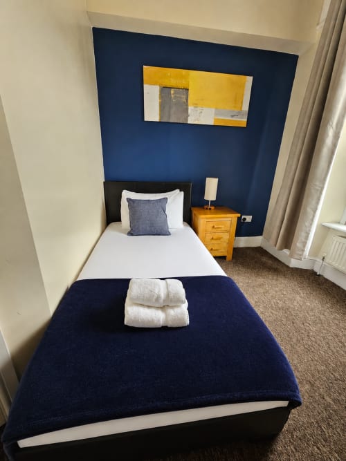 Triple Room at The Cornerhouse Somerset with twin beds, navy feature wall, wooden nightstand, and yellow artwork