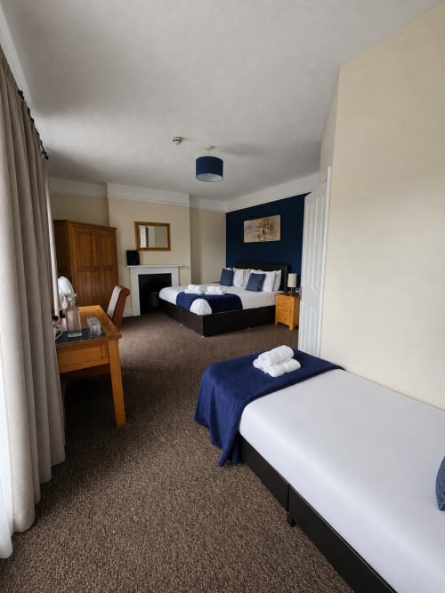 Triple room at The Cornerhouse hotel in Somerset with two beds, fireplace, wooden furniture and navy blue accents