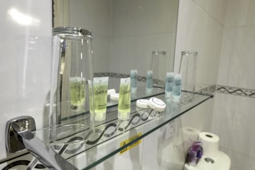 Bathroom shelf at The Cornerhouse hotel displaying complimentary toiletries including shampoo, conditioner, and amenities in