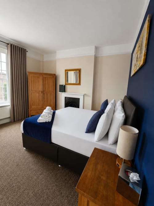 Triple Room at The Cornerhouse hotel in Somerset featuring a bed with navy accents, fireplace, and elegant beige walls