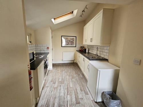 Modern kitchen in One-Bedroom Apartment at The Cornerhouse, Frome, with white cabinetry, stainless steel appliances and wood