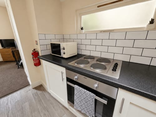 Modern kitchen in One-Bedroom Apartment at The Cornerhouse, Frome with white subway tile, black countertops, electric cooker,