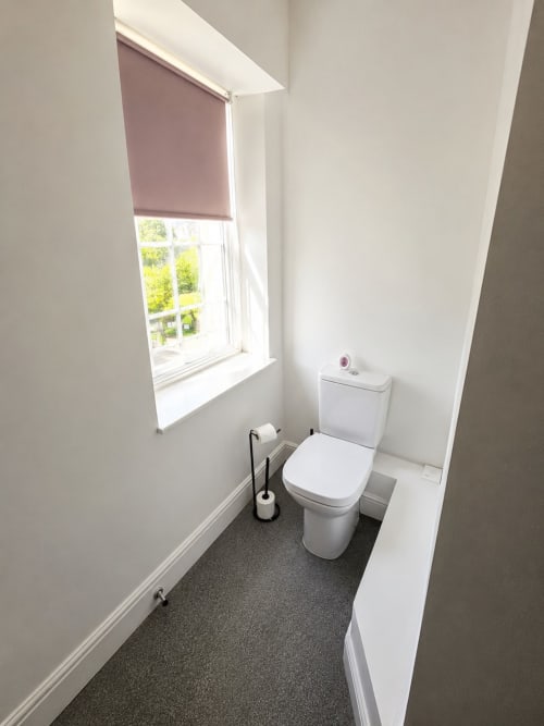 Modern toilet room at The Cornerhouse Somerset hotel with window, white fixtures, and dark flooring
