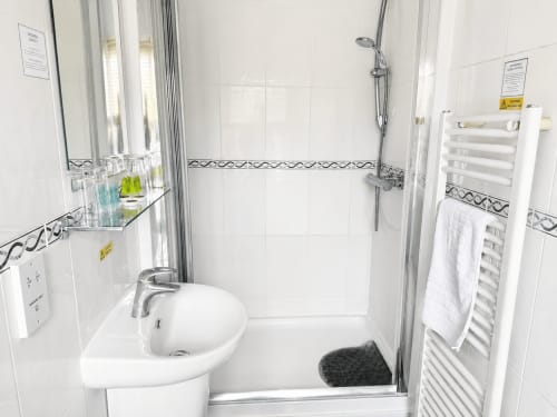 Modern white bathroom with walk-in shower, pedestal sink, and heated towel rail at The Cornerhouse hotel in Somerset