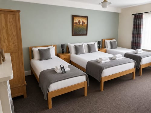 Quadruple room at The Cornerhouse hotel in Somerset with three wooden-framed beds, white linens, grey accents, and