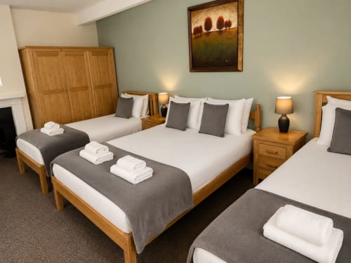 Quadruple room at The Cornerhouse, Somerset with wooden beds, white linens, grey accents, and modern amenities