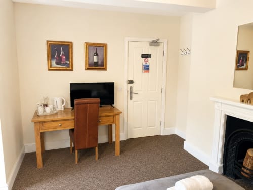 Quadruple Room at The Cornerhouse hotel in Somerset with wooden desk, TV, fireplace, and carpeted flooring