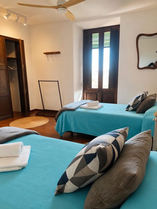 Dormitori brillant amb dos llits turquesos, bigues de fusta i portes franceses a l'Hotel Mas Ribas a Palamós