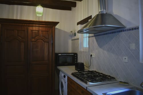 Cuisine moderne du gîte Le Moulin Garnier avec cuisinière au gaz, hotte aspirante et vue sur la rivière