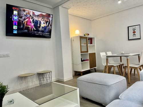 Salón moderno de apartamento en Valencia con Netflix en TV, asientos cómodos, zona de comedor y mobiliario contemporáneo