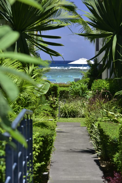 Garden pathway at O'Biches apartment in Trou-aux-Biches leading to ocean view with white umbrella and beach