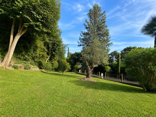 Lush private garden at luxury Cannes apartment with mature trees, manicured lawn, and sea view terrace overlooking Californie