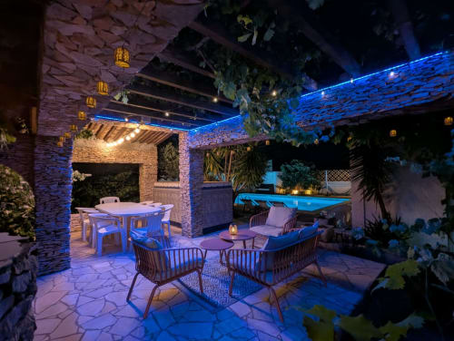 Cottage Le Minervois à La Closerie, La Redorte : terrasse illuminée au bord de la piscine avec coin repas et salon de détente en soirée